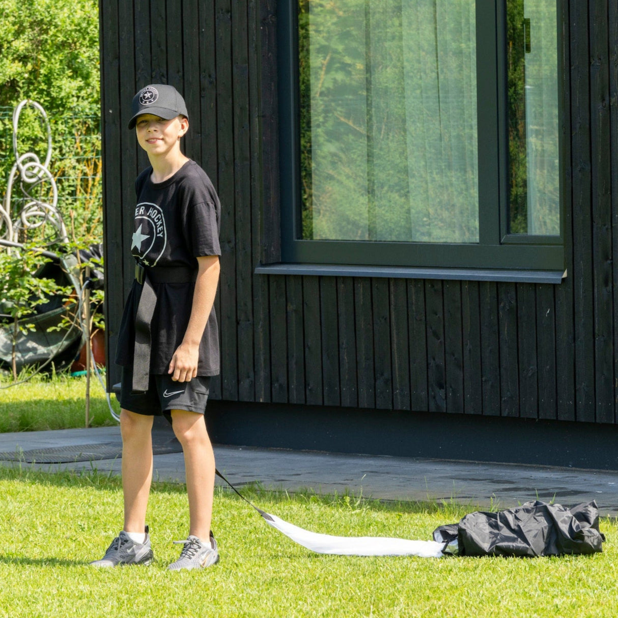 Ung sportutövare med Extreme Hockey Speed Chute som tränar explosivitet i trädgården.