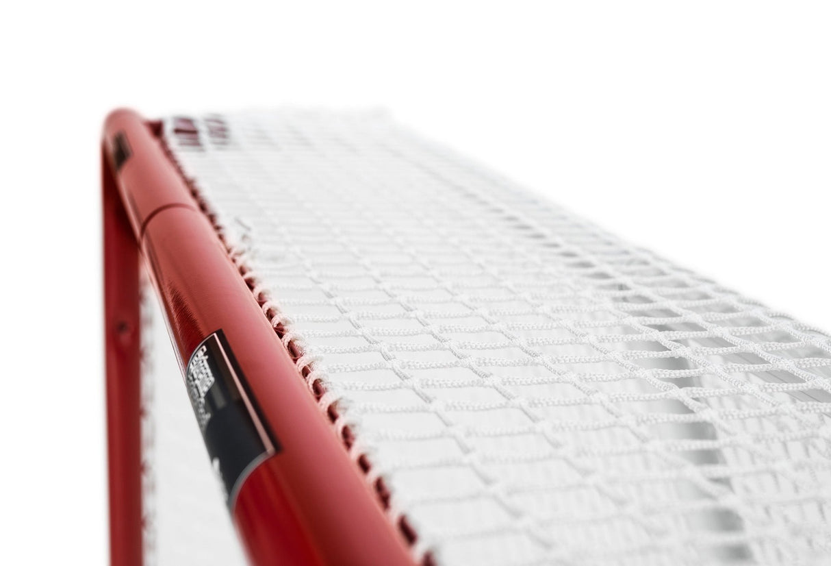 Detalj av ett hockeymål med vitt skyddsnät och röd ram, perfekt för att förbättra precisionen i hockeyträning.