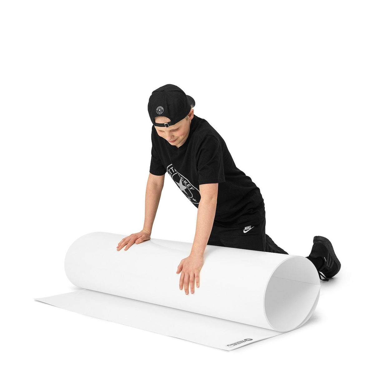 En ung hockeyspelare rullar ut en skottplatta på golvet för att träna skott och passeringsfärdigheter.