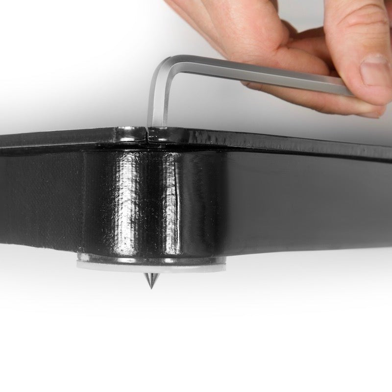 En hand justerar en del av en hockeypassare med ett verktyg, visar den robusta konstruktionen av svart stål.