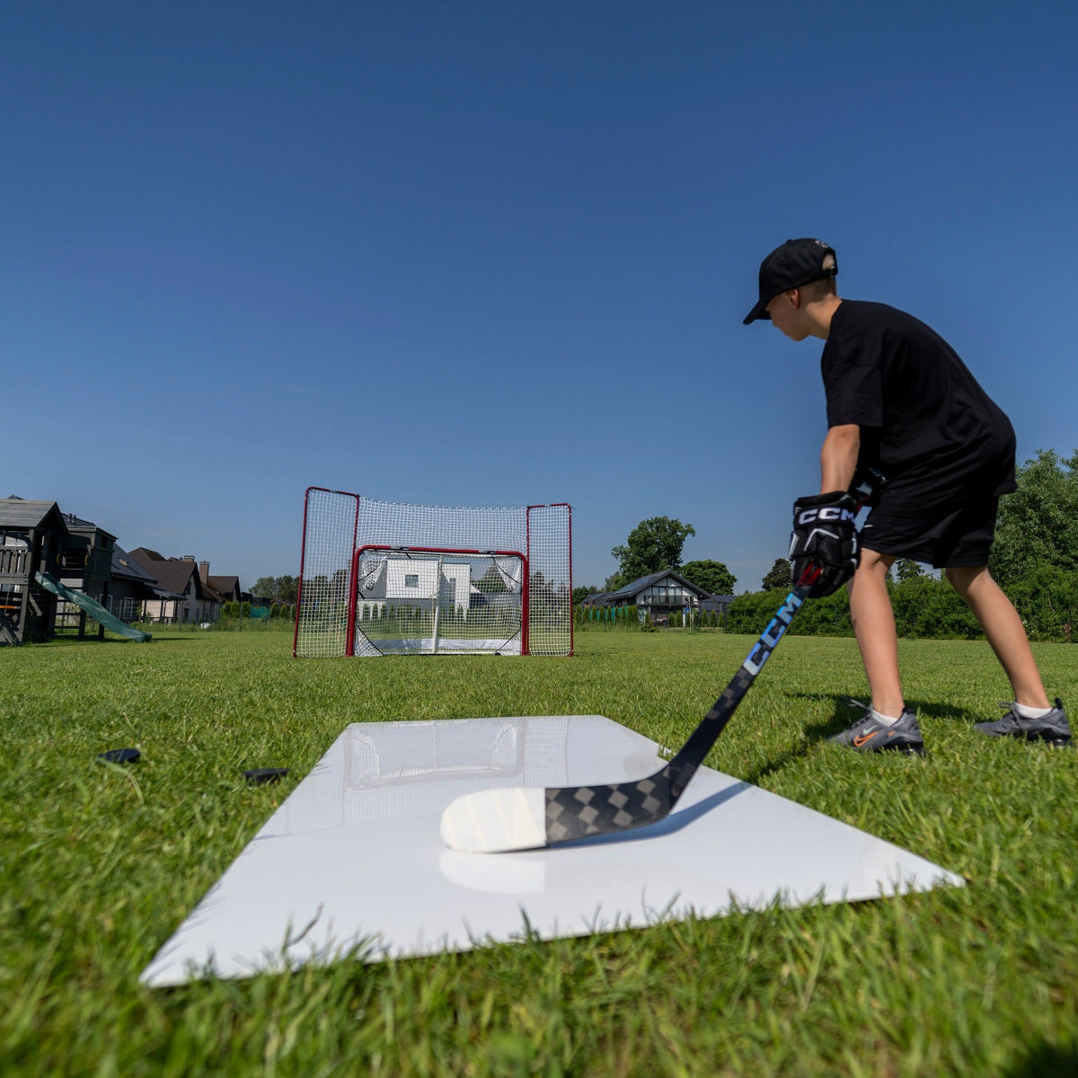 Young hockey player lining up a shot from a shooting pad toward a net in the backyard