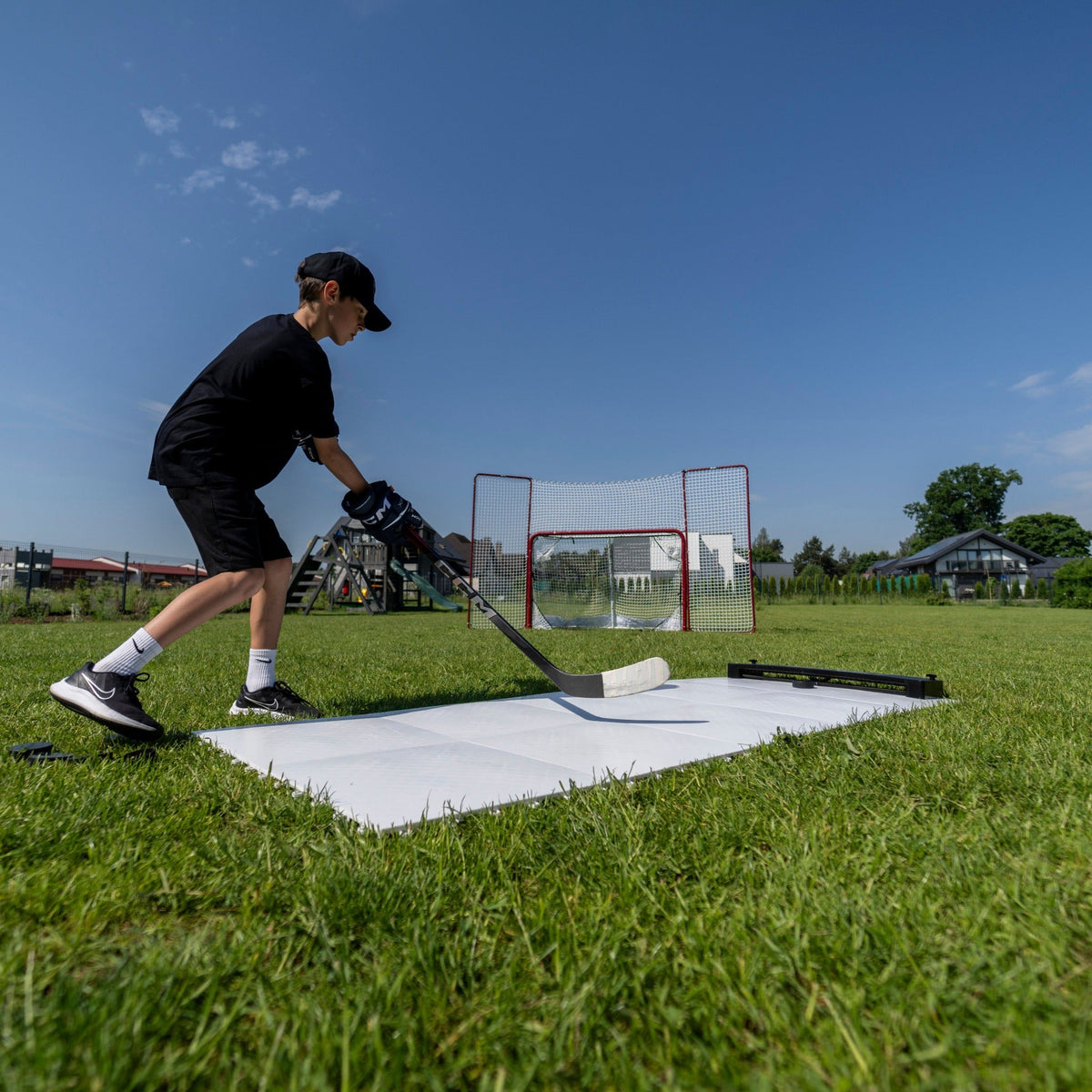 Youth hockey player training with flooring tiles and passing kit in the backyard — off-ice special teams setup