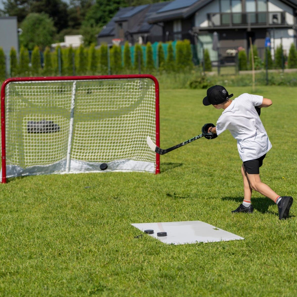 Young hockey player shooting pucks in the backyard on a Better Hockey shooting pad