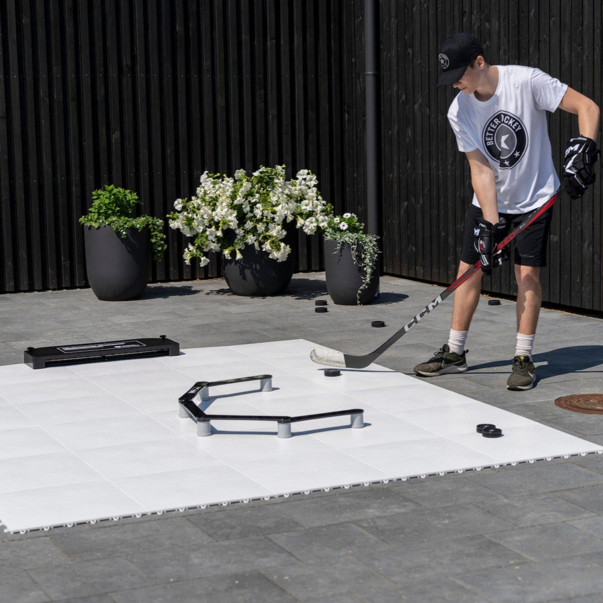 Hockey player in sneakers training stickhandling with a puck on slick training tiles at home