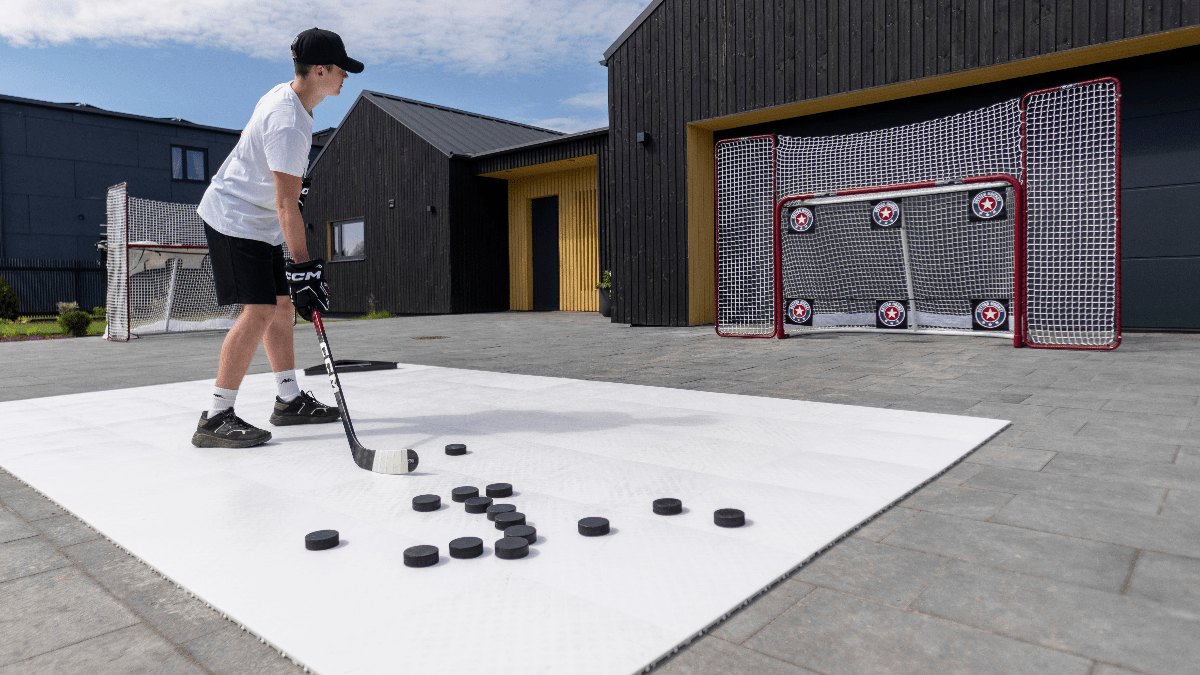 Ung spelare övar med skottavlor och puckar på en uppsättning utomhus, perfekt för att förbättra precision i hockey.
