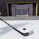 Hockeygolv med puck och klubba framför en målbur, perfekt för träning och skottramp med Plastis Extreme Flooring.