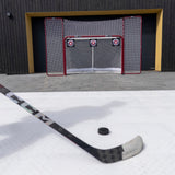 Hockeymål med skottavlor, hockeyklubba och puck i förgrunden, perfekt för träning och förbättrad träffsäkerhet.