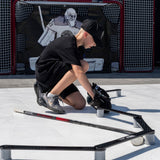 Ung kille sätter på sig skridskor på hockeyträning med klubbteknik stickhandlingstränare.
