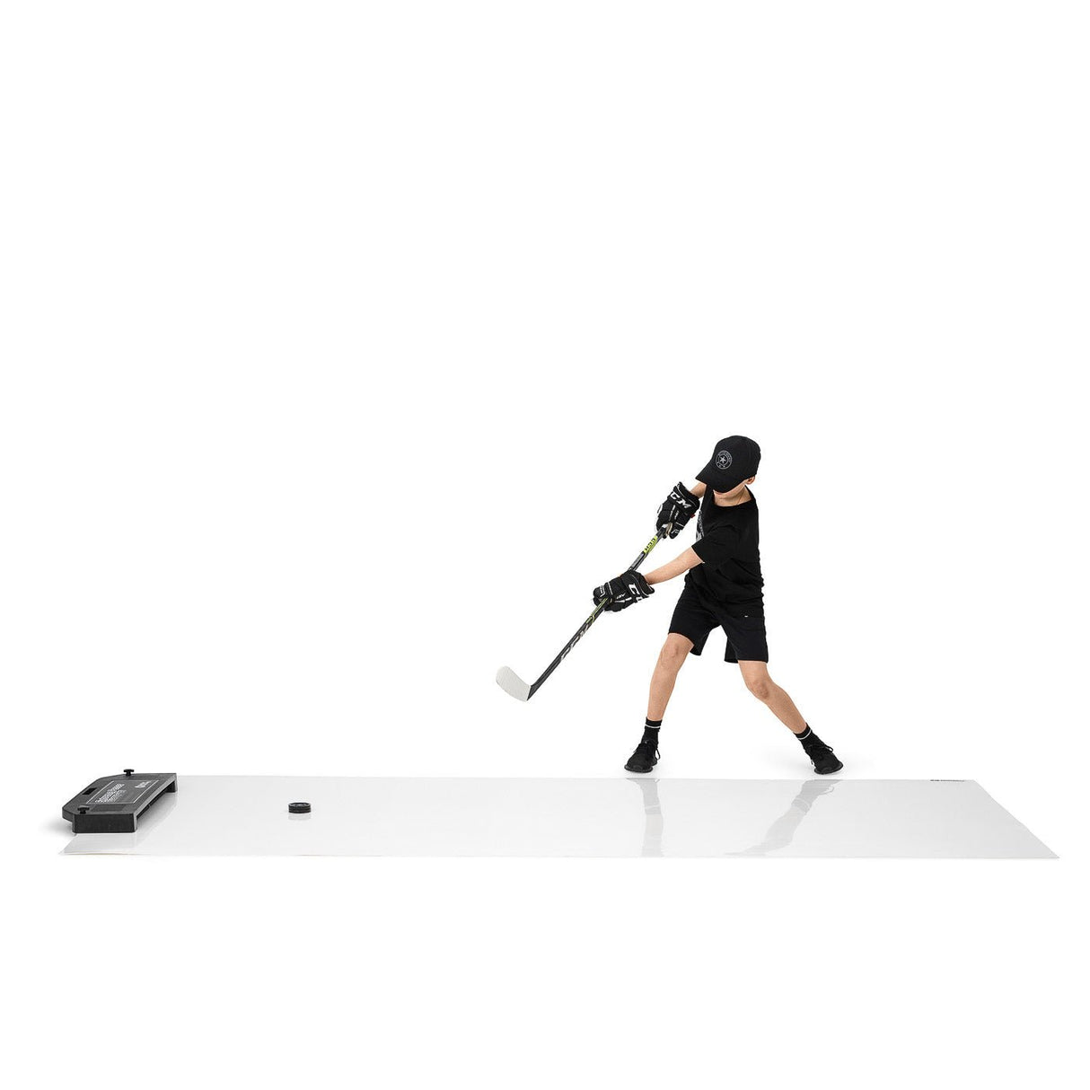 Ung hockeyspelare tränar på en skottplatta med en puck, och förbättrar sina skott och passningar med Extreme Hockey Passing Kit Pro XL.