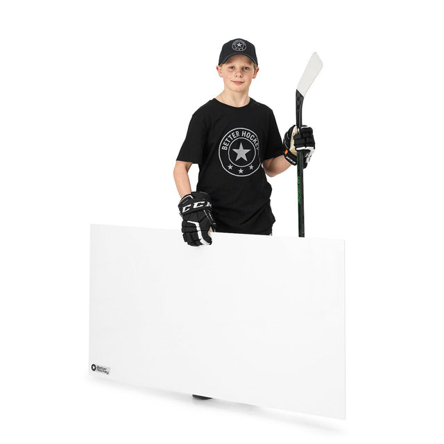 Ung pojke håller en hockeyskottplatta i handen, klädd i t-shirt och handskar, redo att träna sina hockeyskills.