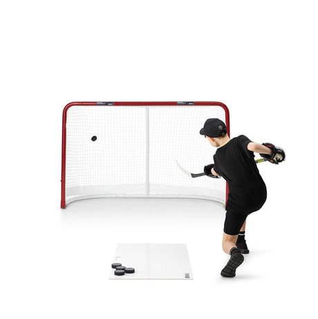Ung hockeyspelare som tränar skott med skottramp mot ett mål, perfekt för att förbättra hockeyfärdigheter.